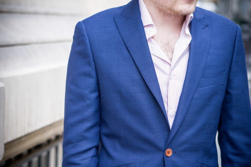 man wearing one button blue suit with inner stripe polo shirt