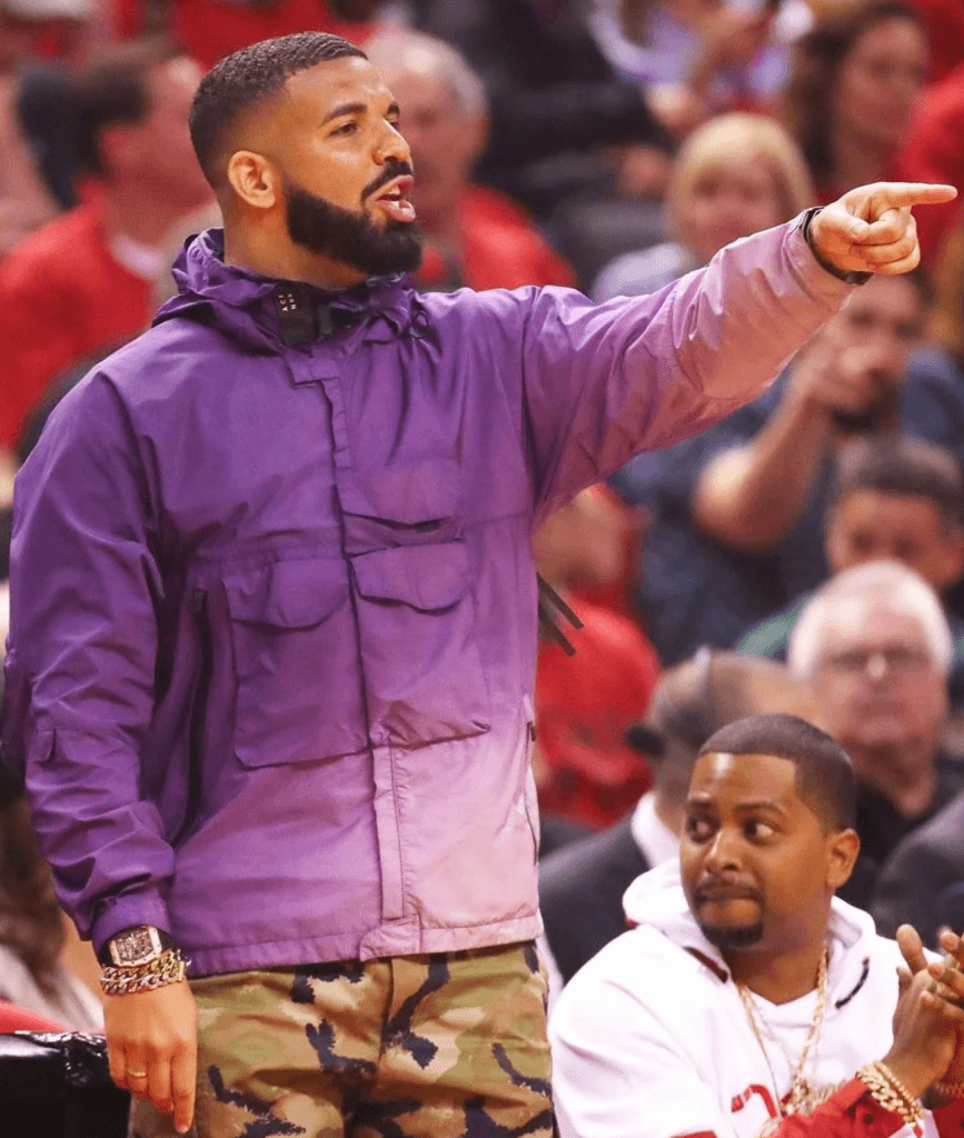 Drake in a purple hardshell jacket and fatigues.